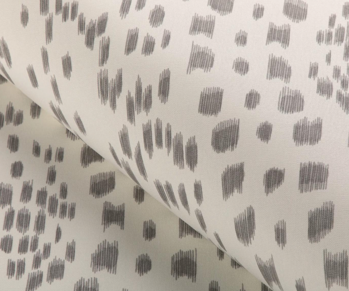 Close-up of Les Touches pillow cover in gray featuring an abstract pattern of short vertical and horizontal brushstroke clusters on a light background.