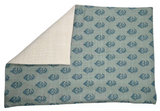Rectangular pillow cover in muted blue with repeating dark blue floral motifs, folded to show its plain beige reverse side with a woven texture.
