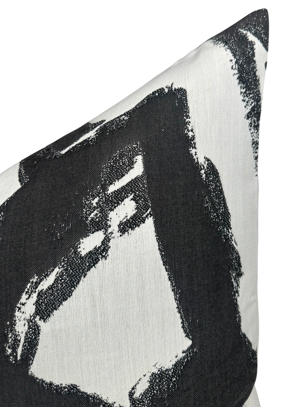 Close-up of a pillow cover featuring bold black brushstroke patterns on a white fabric background, showing texture and sharp contrast.