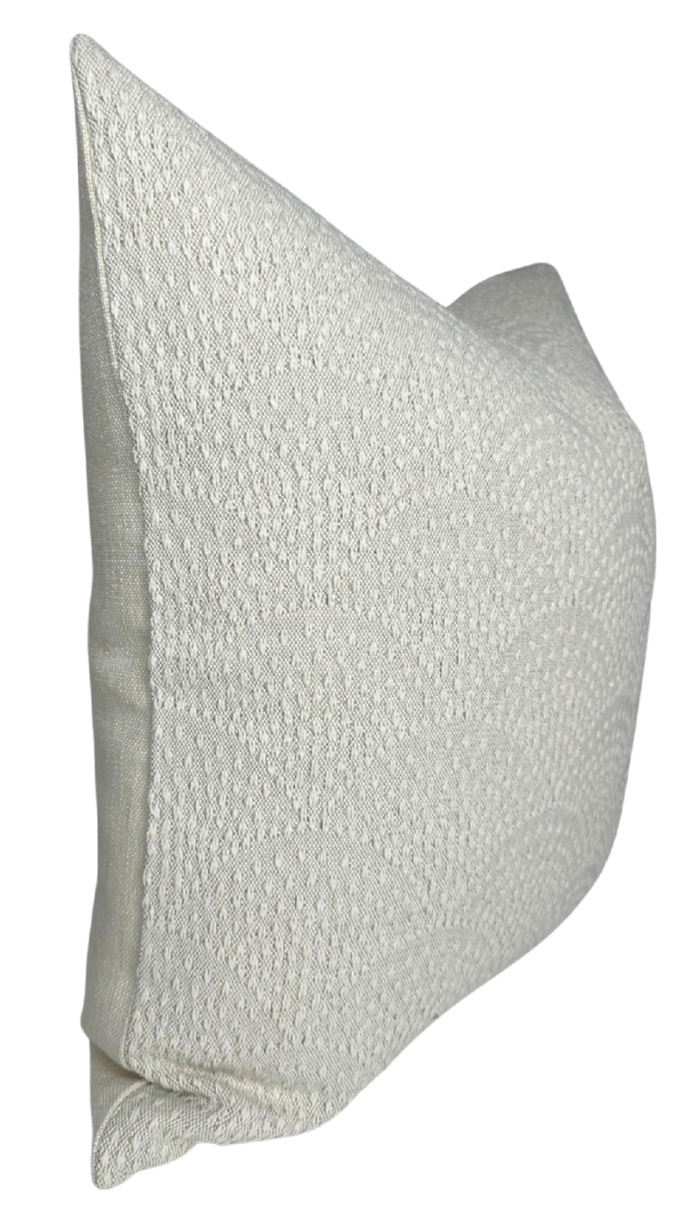 Rectangular natural-colored woven pillow cover featuring a subtle inverse scalloped textured pattern, shown angled against a white background.