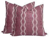 Two square pillow covers in dusty rose with vertical wavy white embroidered stripes, arranged slightly overlapping on a white background.