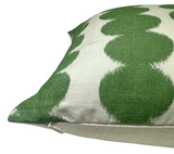 Close-up of a pillow cover with rows of large green circular brushstroke patterns on an off-white textured fabric and a visible corner zipper.