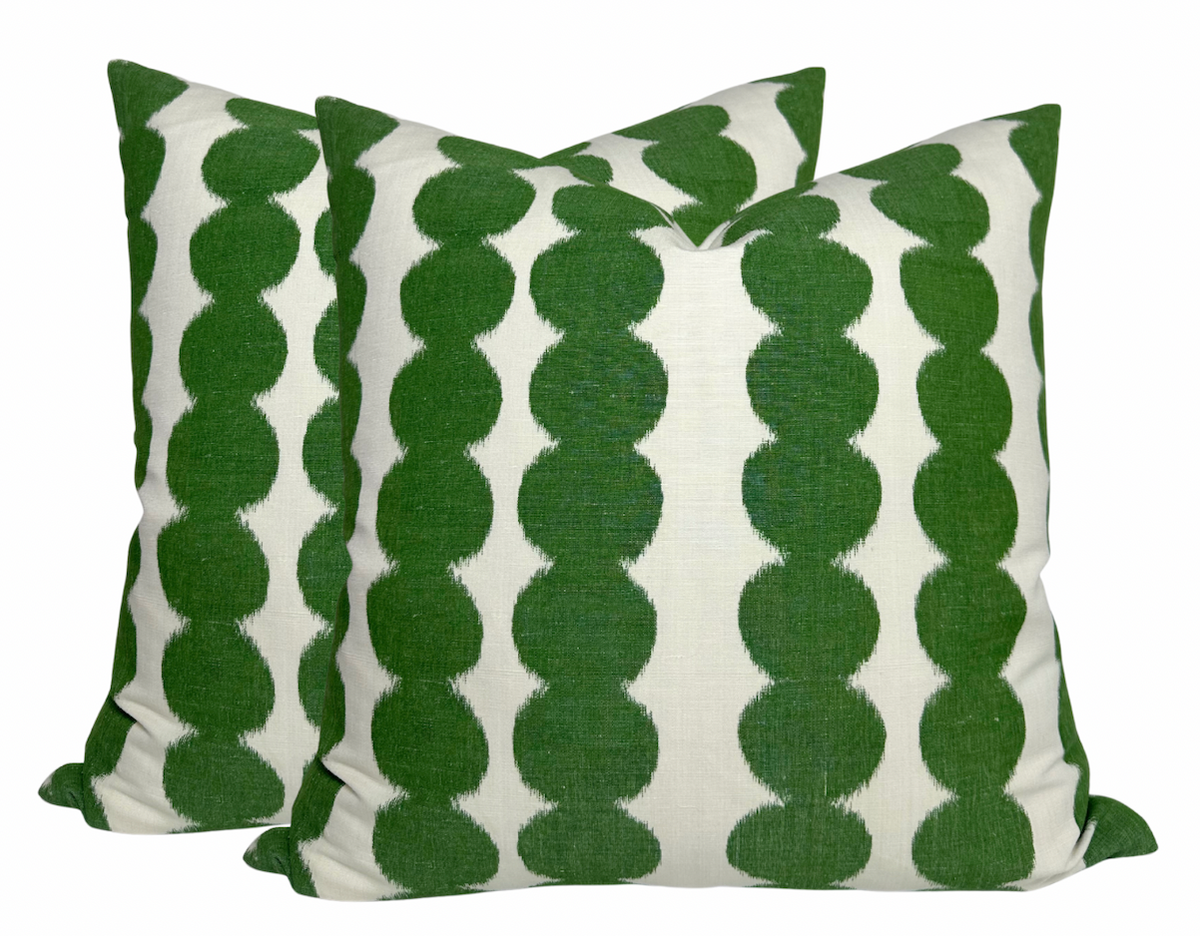 Two square pillow covers with a repeating vertical pattern of connected green circular shapes on a white background.