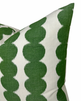 Close-up of a pillow cover featuring a repeating pattern of large, rounded green shapes on a white background, showing fabric texture and sharp color contrast.