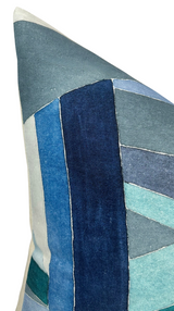 Close-up of a pillow corner featuring a patchwork design in various shades of blue with visible stitching and textured fabric.