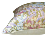 Close-up of a linen pillow cover featuring a floral pattern with soft blush, blue, and green hues, showing a visible zipper along the edge.