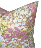 Close-up of a linen pillow cover featuring a floral pattern with white, yellow, and purple flowers on a blush pink background.