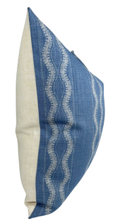 Square pillow cover with natural beige linen back and indigo blue front featuring wavy white geometric stripe patterns, shown from a side angle.