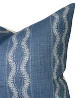 Close-up of an indigo blue pillow cover featuring vertical wavy white embroidered lines on a textured woven fabric background.