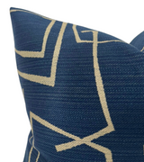 Close-up of an indigo pillow cover with an abstract geometric pattern in beige lines on textured fabric.