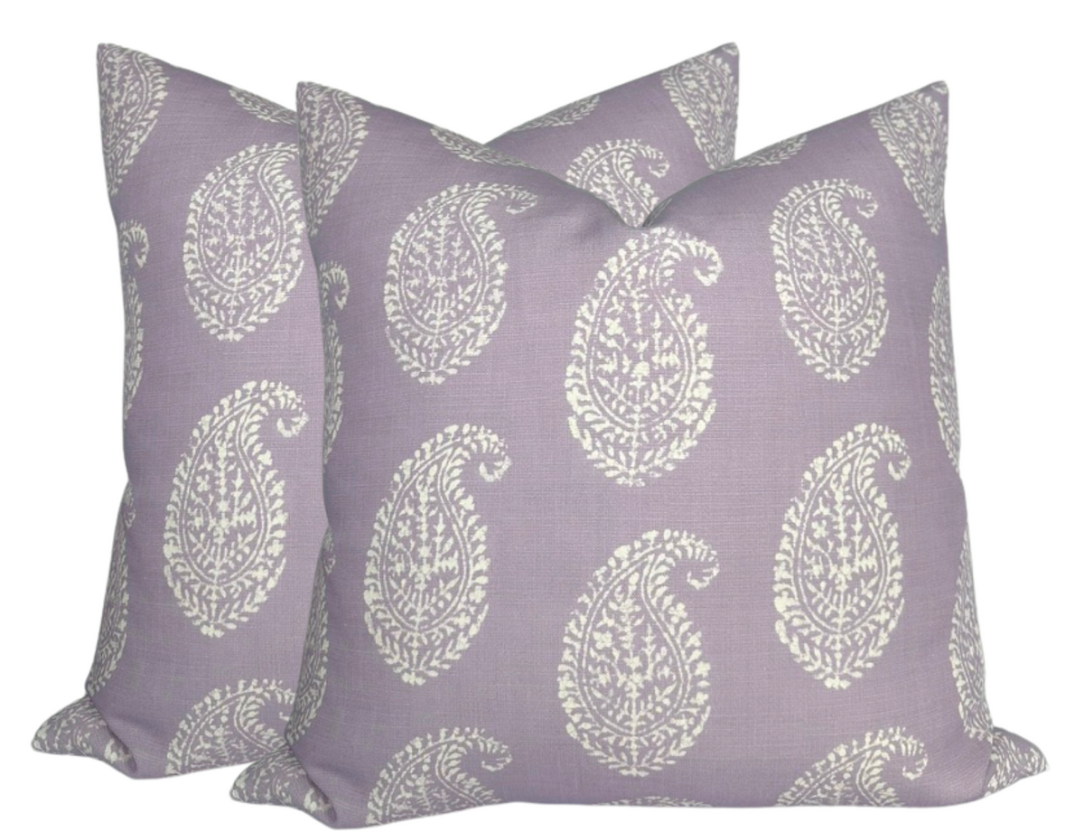 Two lilac purple pillows with large white intricate paisley patterns evenly spaced on fabric, stacked against a white background.