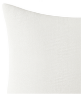 Close-up of a white textured fabric pillow cover with a subtle woven pattern and a slightly visible seam along the edge.