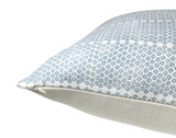 Close-up of a rectangular pillow with a blue floral pattern on a white fabric top and plain off-white textured fabric on the sides.