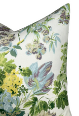 Close-up of a pillow cover with a botanical watercolor pattern featuring soft green, purple, yellow, and blue leaves and flowers on a white background.