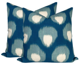 Two square pillow covers with a blue background featuring a repeating pattern of white teardrop shapes outlined in teal, shown slightly overlapping on a white background.