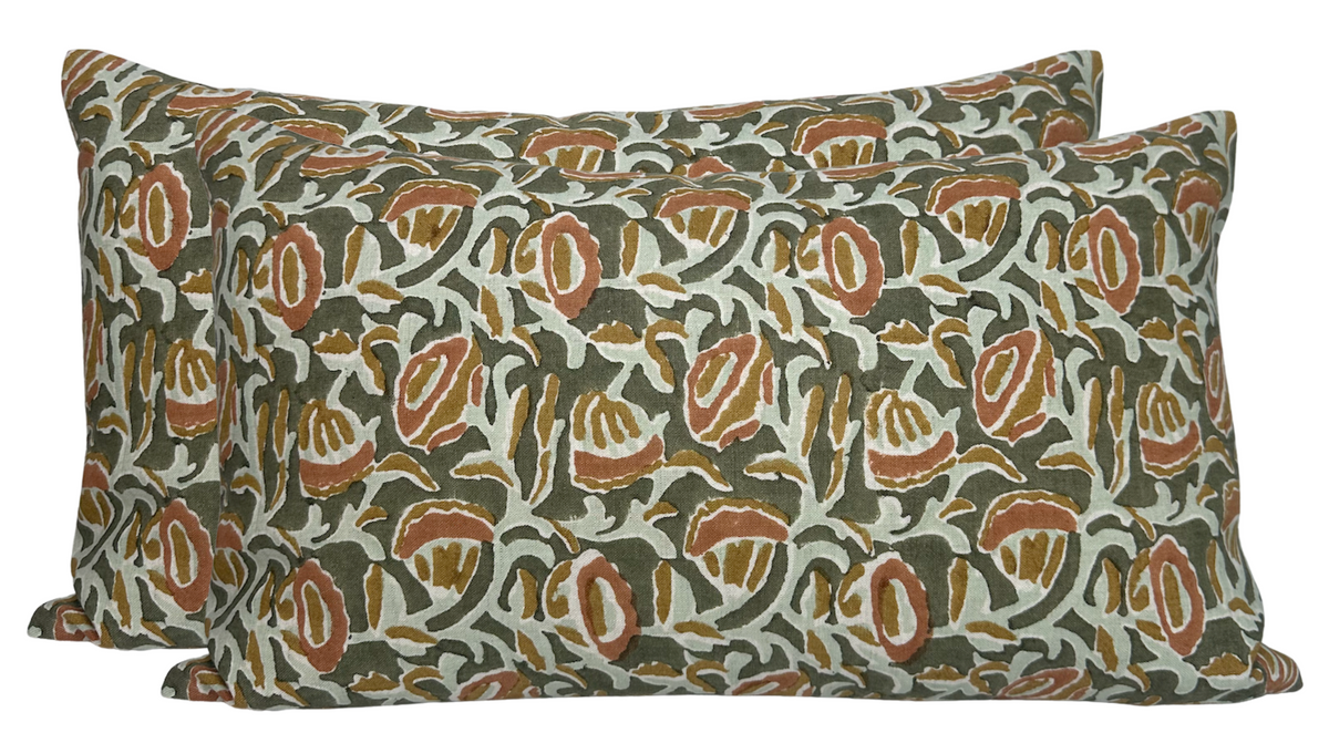 Rectangular pillow covers with an intricate pattern of rust and olive shapes on a light beige background, featuring a piped edge detail.