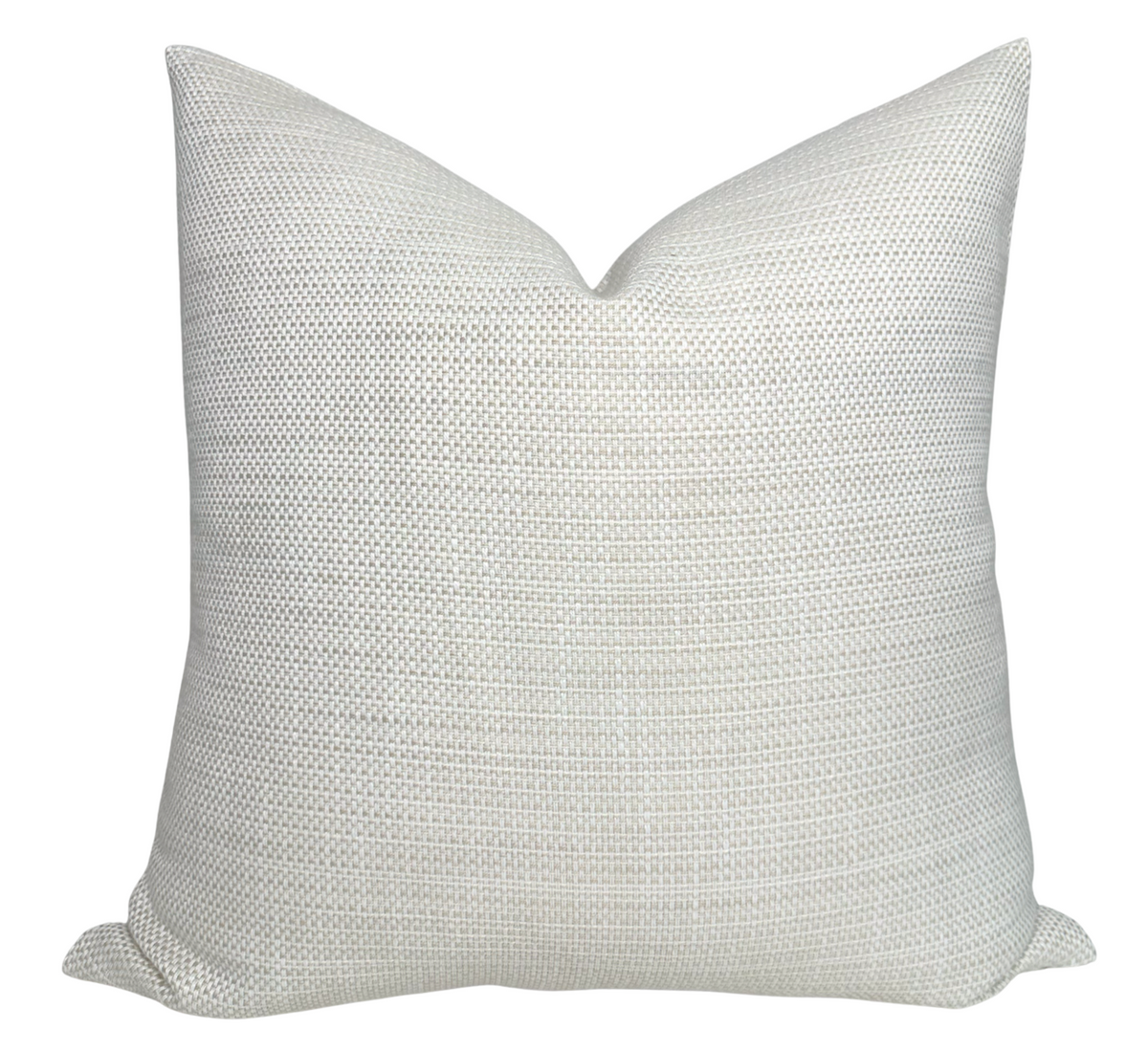 Kravet Woven Pillow Cover in Tan displayed on a wooden surface with a cozy interior backdrop