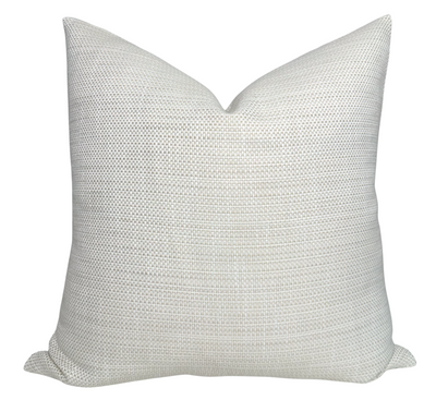 Kravet Woven Pillow Cover in Tan displayed on a wooden surface with a cozy interior backdrop