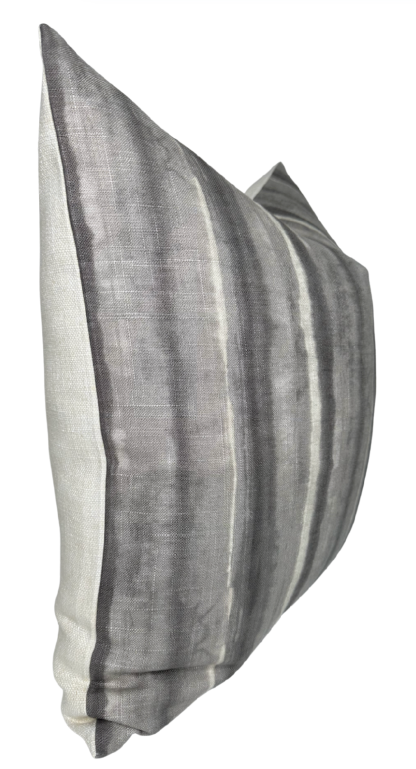 Rectangular pillow cover with charcoal and gray vertical stripes in a subtle watercolor effect on a light ivory background, shown slightly angled.