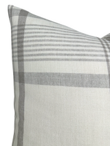 Close-up of a beige pillow cover featuring a subtle plaid pattern in various shades of gray, highlighting the fabric's texture and stitched edges.