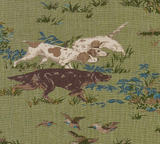 Fabric with a meadow green background featuring a detailed print of three pointing dogs in white, brown, and black amid scattered blue floral accents and grasses.