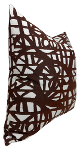 Rectangular pillow with an abstract dark rust pattern of intersecting lines and shapes on a white background, shown angled with a v-shaped top corner.
