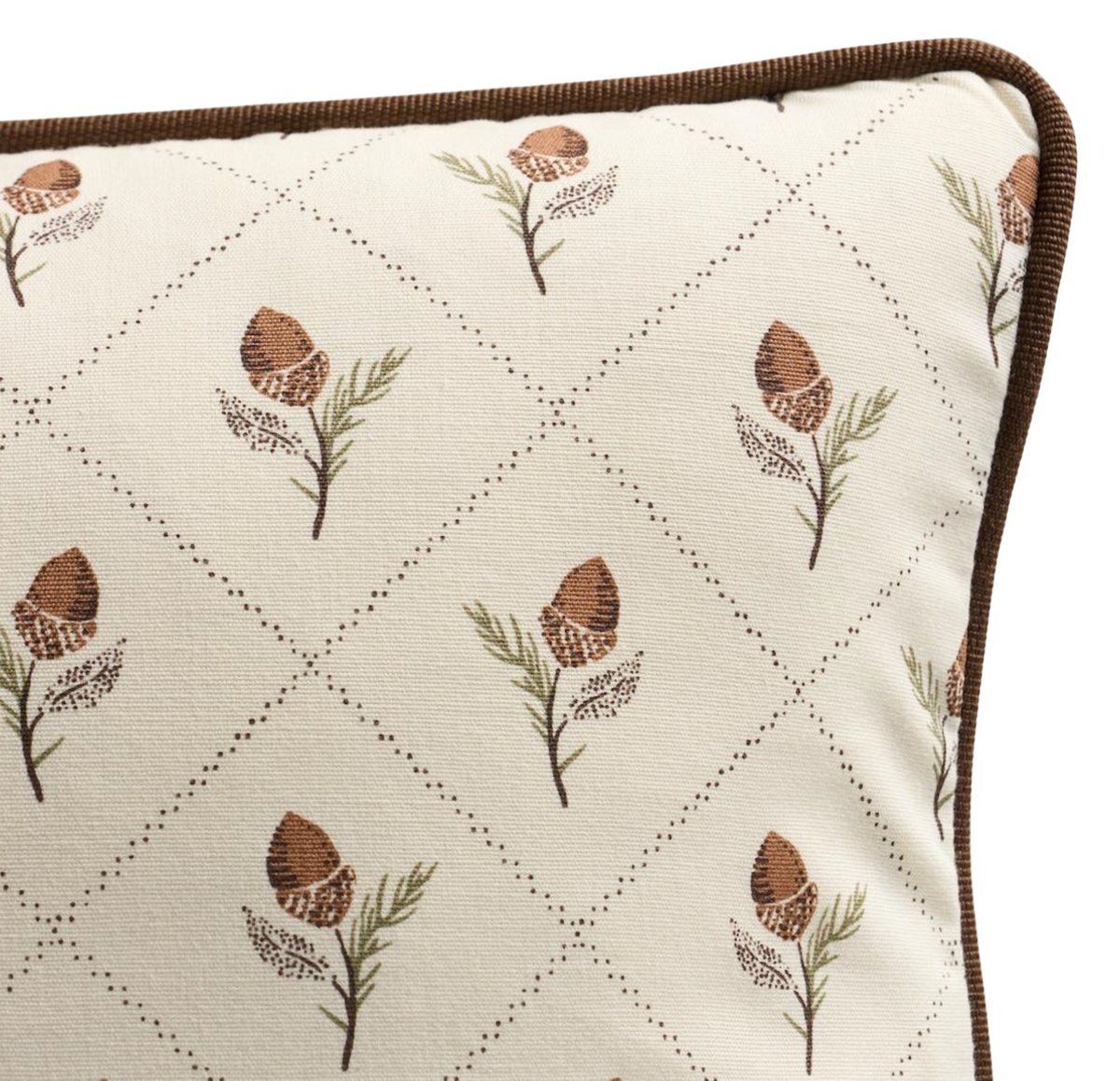 Close-up of cream pillow cover with brown piping featuring a repeated pattern of brown pinecone-like motifs with green and brown sprigs in diamond grid lines.