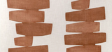 Soft fabric pillow cover with stacked, irregular horizontal shapes in muted clay brown on a light beige background.