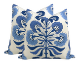Pair of square pillows with blue botanical tree design on white background, featuring large stylized leaves and curved floral shapes.
