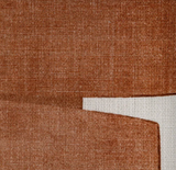 Close-up of two overlapping clay-colored pillow covers with a textured woven fabric on a light beige woven surface.