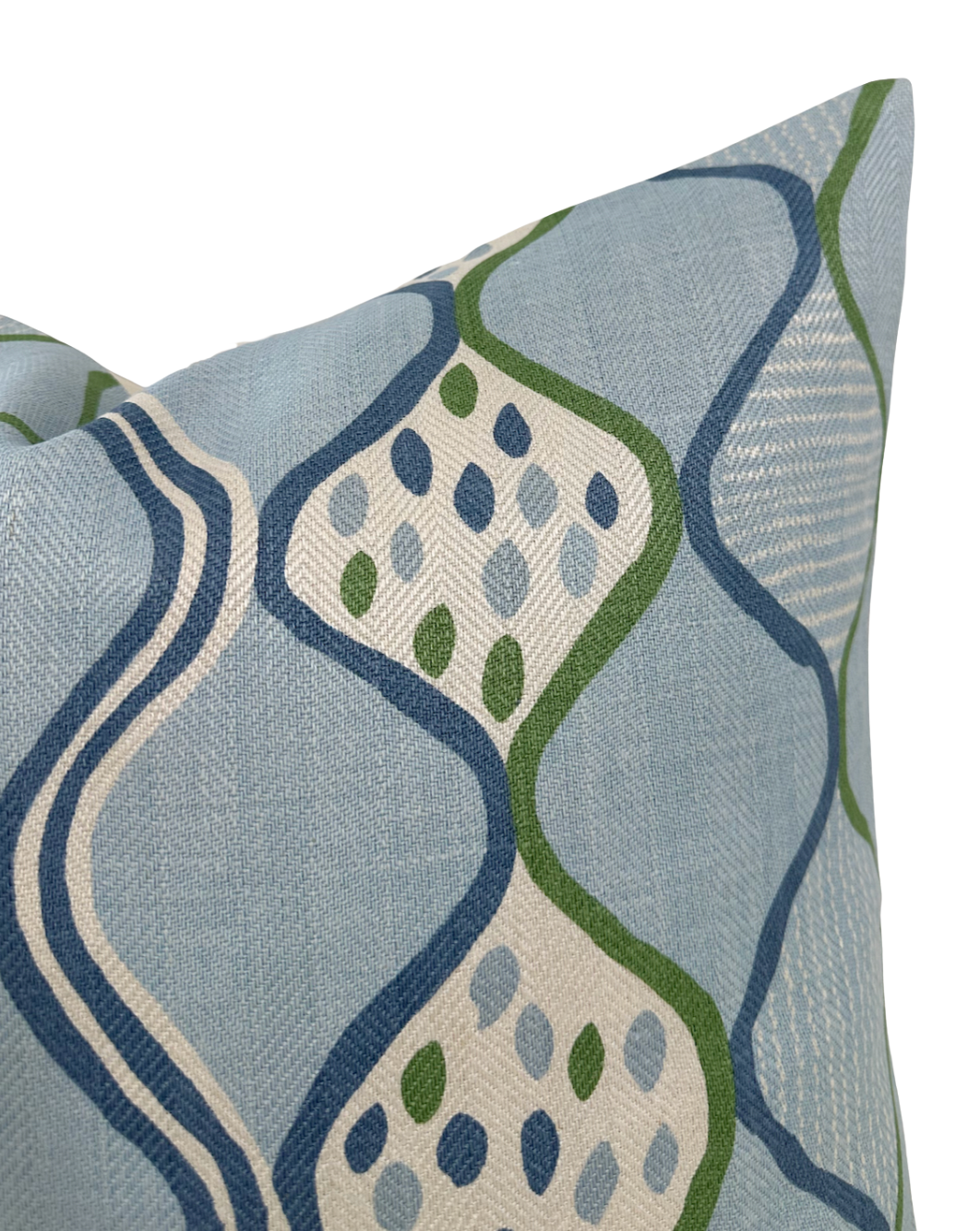 Close-up of a pillow cover with a wavy blue and green pattern and small leaf shapes inside the waves on a light blue textured fabric.