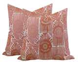 Three square throw pillows with a repeating pattern of circular and linear coral, pink, and beige designs on a fabric cover.