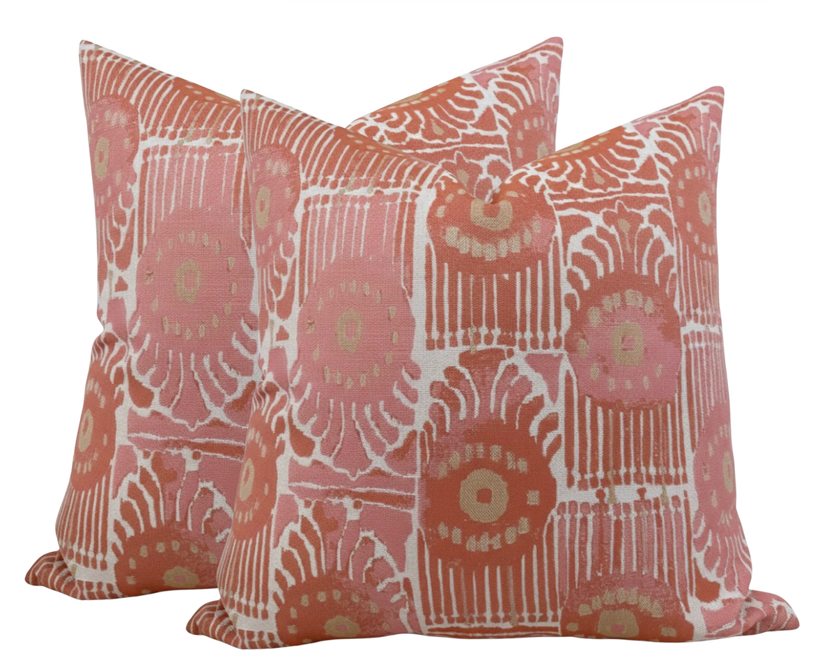 Three square throw pillows with a repeating pattern of circular and linear coral, pink, and beige designs on a fabric cover.