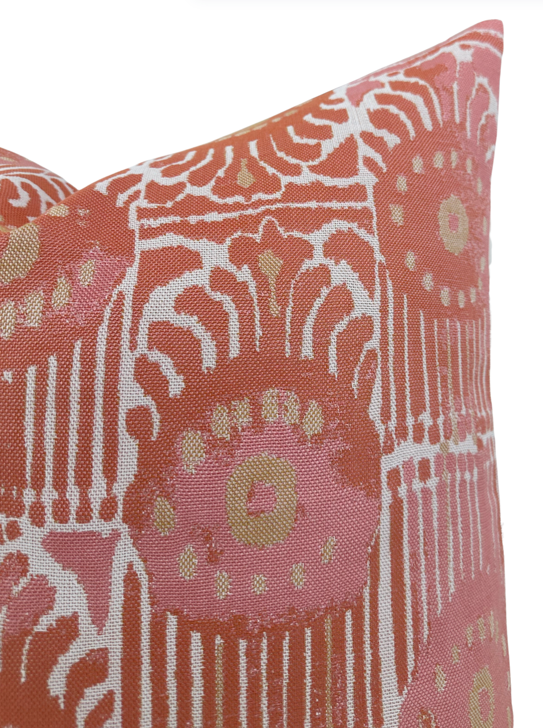 Close-up of a melon-colored pillow cover with a white and gold abstract floral and geometric pattern on textured fabric.