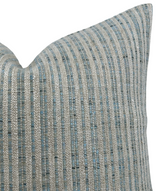 Close-up of an aqua blue and silver striped woven pillow cover with a textured pattern and a pointed corner.