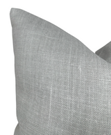 Close-up of a soft gray linen pillow cover with a subtle woven texture, shown against a white background highlighting its fabric detail.
