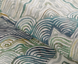 Close-up of fabric with curved, wave-like patterns in shades of green, teal, and beige overlapping each other.