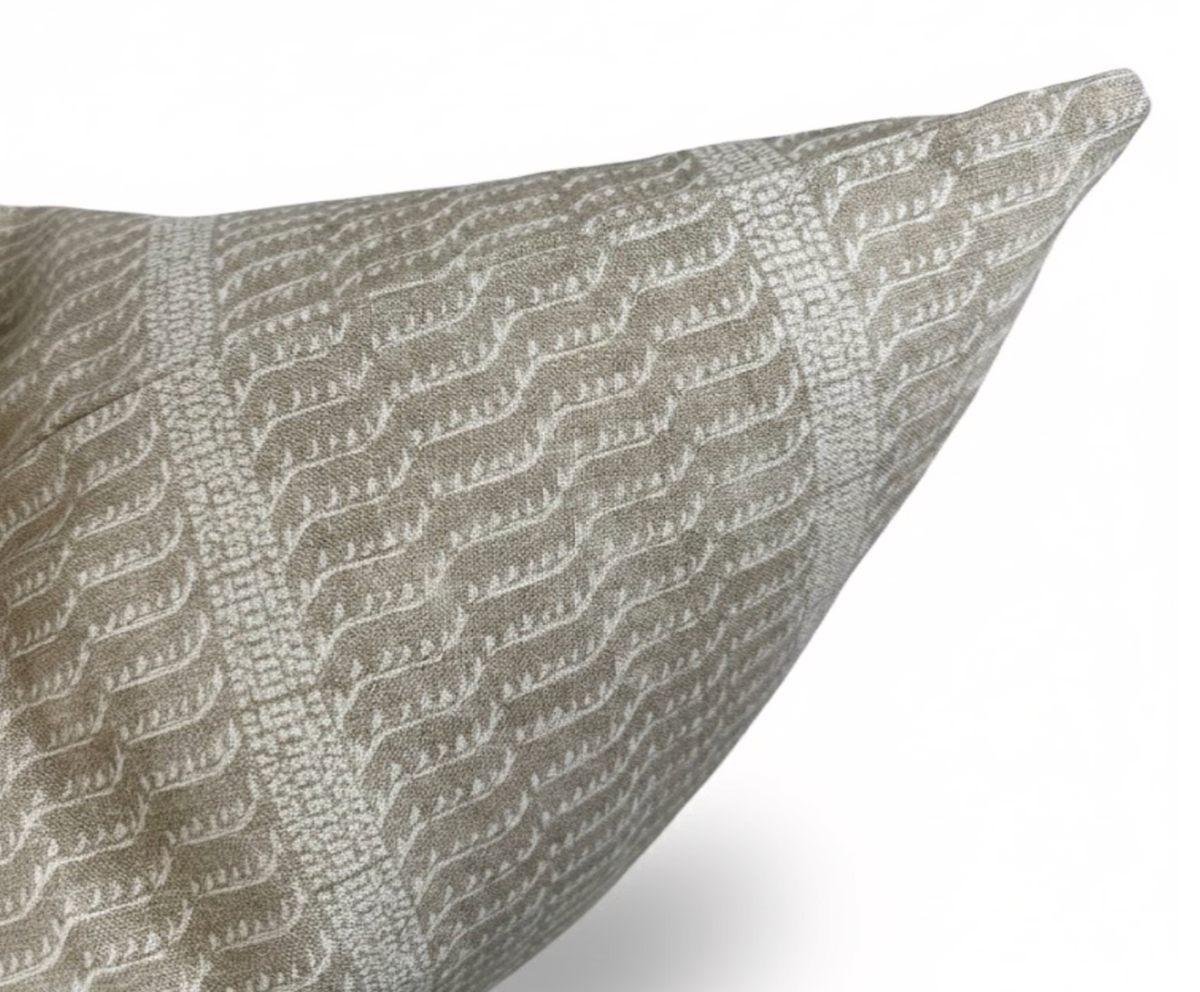 Close-up of a pillow corner featuring a woven beige and off-white pattern with vertical textured stripes and abstract leaf motifs on a soft fabric.