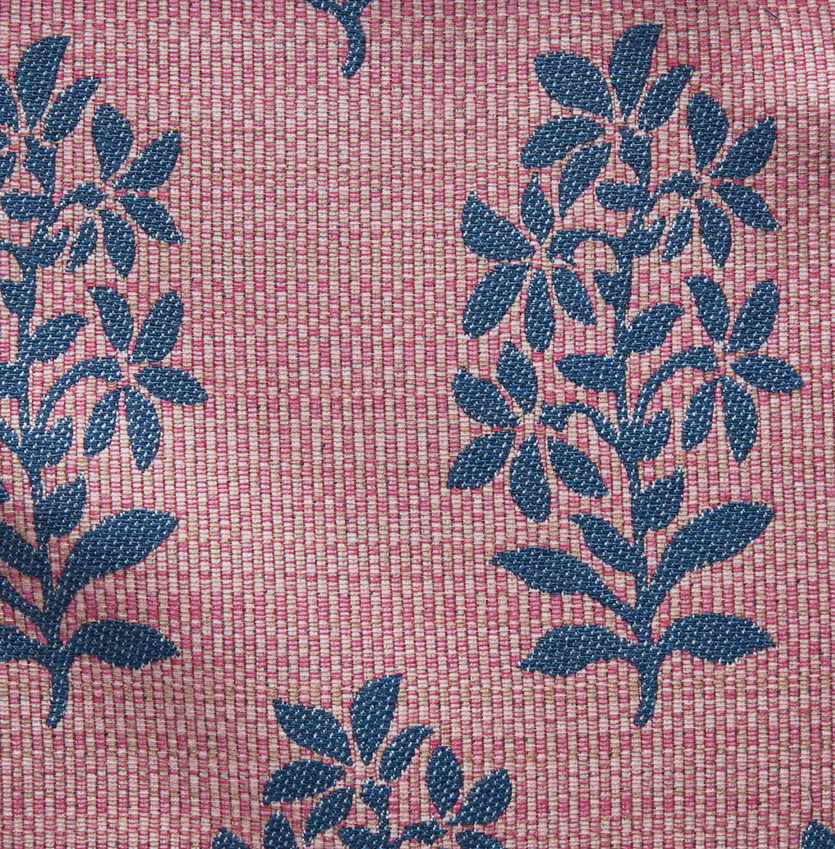 Pink woven fabric featuring a repeating pattern of blue leafy branches with textured detailing, creating a subtle contrast between the background and design.