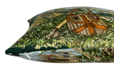Close-up side view of a pillow cover with a detailed hunting-themed print depicting a woven basket and a rifle among green grass and ducks.