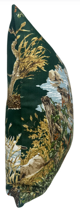 Side view of a pillow cover with dark green background featuring detailed naturalistic prints of trees, branches, and water in earthy brown, beige, and blue tones.