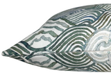 Close-up of a pillow cover featuring overlapping circular and wavy line patterns in shades of green and blue on a white fabric background.