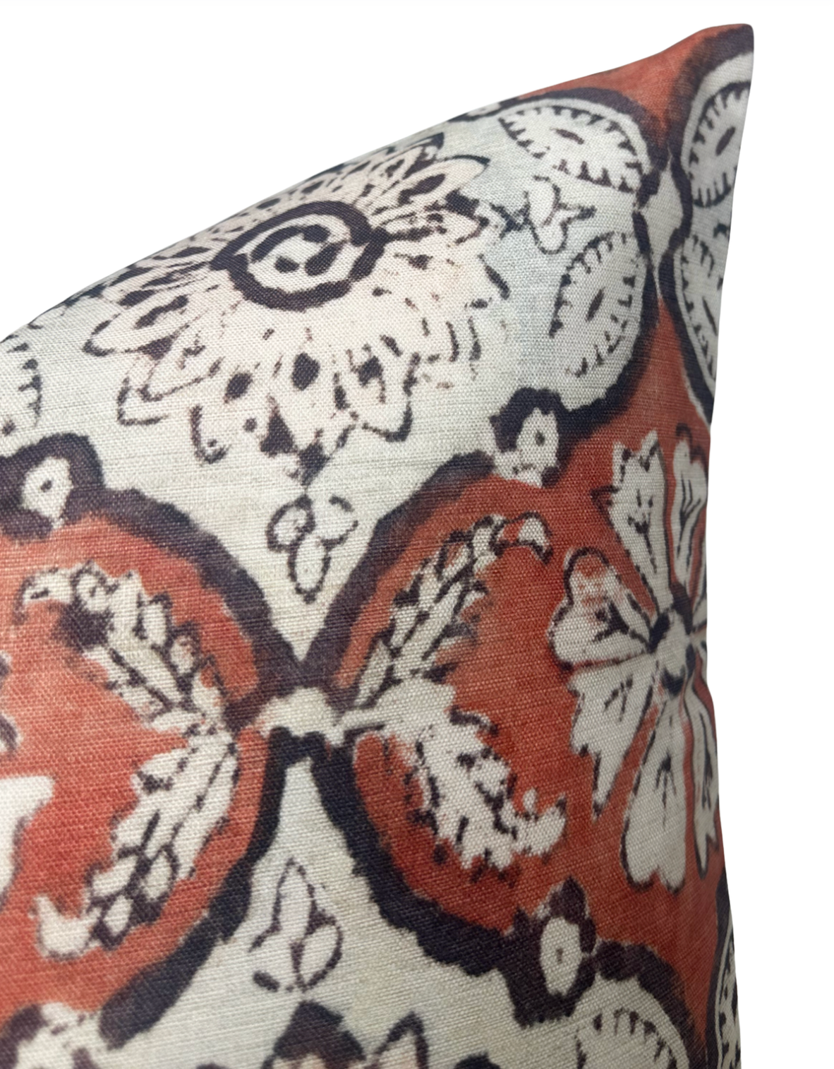 Close-up of a pillow corner featuring a floral and medallion pattern in ruby red, cream, and black on woven fabric.
