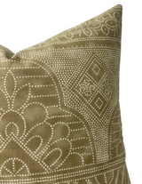 Close-up of a camel brown pillow cover with an intricate white dotted geometric and floral pattern on fabric.
