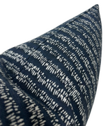 Close-up of a blue woven pillow cover with an alternating white dashed and linear pattern creating a textured striped design.