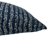 Close-up of a rectangular pillow with a woven Atlantic blue fabric featuring irregular vertical white stitch-like stripes, showing the corner and seam detail.