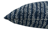 Close-up of a blue and white woven pillow cover with irregular striped pattern and a small silver zipper on one side.