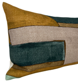 Rectangular pillow with abstract geometric pattern in tobacco brown, tan, teal, and muted green colors, showing textured woven fabric and sharp color contrasts.
