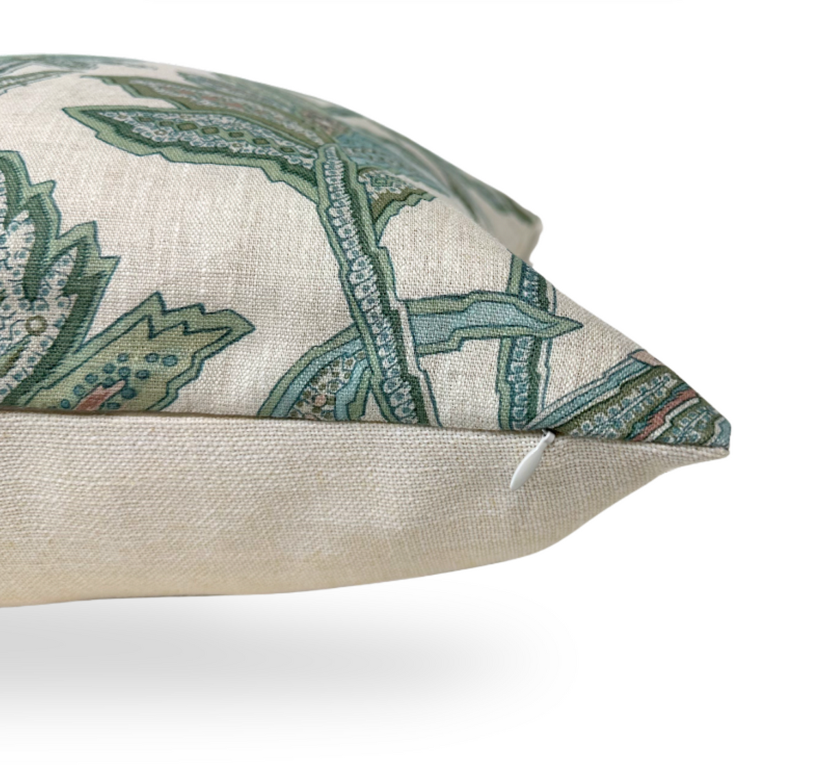 Close-up of a beige pillow corner featuring a sage green and muted blue floral pattern with a hidden zipper along the seam