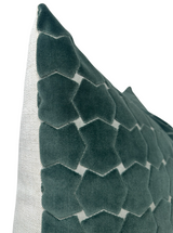Close-up angled view of a seafoam green velvet pillow cover with raised hexagon pattern on a light gray fabric base.
